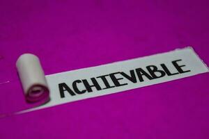 Achievable text, Inspiration and positive vibes concept on purple torn paper photo