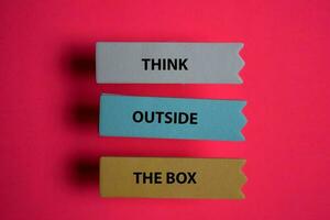 Think Outside The Box write on a sticky note isolated on Office Desk. photo