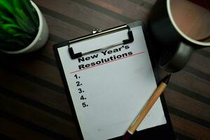 New Years Resolutions write on a paperwork isolated on Wooden Table. photo