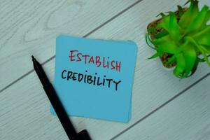 Establish Credibility write on sticky notes isolated on Wooden Table. photo