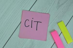 Concept of CIT - Corporate Income Tax write on sticky notes isolated on Wooden Table. photo