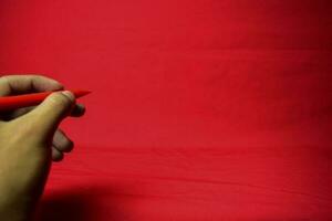 Man hand with red pen writing on red background photo