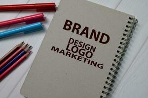 Brand, Design, Logo Marketing write on a book isolated on wooden table. photo