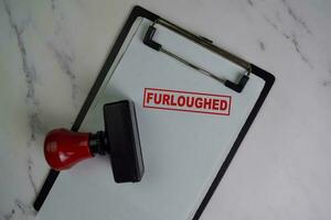 Red Handle Rubber Stamper and Furloughed text isolated on wooden table. photo