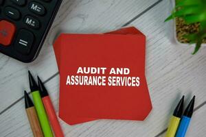 Audit and Assurance Services write on sticky notes isolated on Wooden Table. photo
