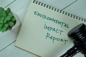 Concept of Environmental Impact Report write on a book with gavel isolated on Wooden Table. photo