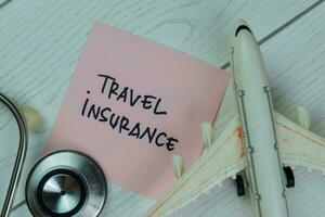Travel Insurance write on sticky notes isolated on Wooden Table. photo