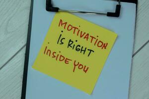 Concept of Motivation Is Right Inside You write on sticky notes isolated on Wooden Table. photo