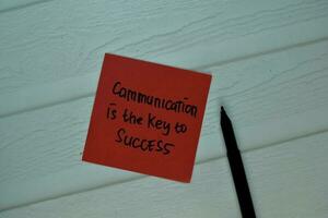 Communication is the key to success write on sticky note isolated on Wooden Table. Selective focus on Communication is the key to success text photo