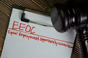 EEOC - Equal Employment Opportunity Commission write on a paperwork isolated on Wooden Table. photo