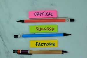 Concept of Critical, Success, Factors write on sticky notes isolated on Wooden Table. photo