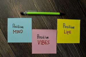 Positive Mind, Positive Vibes, Positive Life write on sticky note isolated on Wooden Table. photo