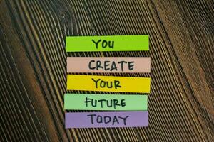 You Create Your Future Today write on sticky notes isolated on Wooden Table. photo