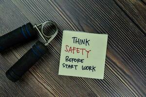 Think Safety Before Start Work write on sticky notes isolated on Wooden Table. photo