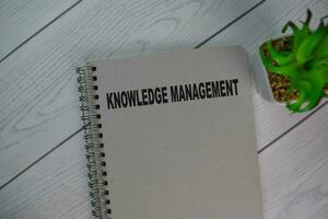 The book of Knowledge Management isolated on Wooden Table. photo