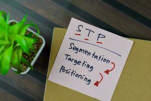 Concept of STP - Segmentation Targeting Positioning write on sticky notes isolated on Wooden Table. photo