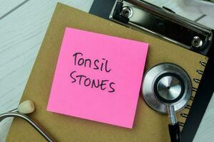 Concept of Tonsil Stones write on sticky notes isolated on Wooden Table. photo