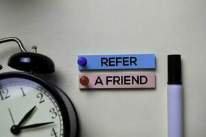 Refer A Friend text on sticky notes isolated on office desk photo
