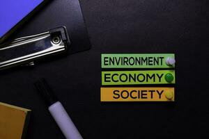 ambiente, economía, sociedad texto en pegajoso notas aislado en negro escritorio. mecanismo estrategia concepto foto