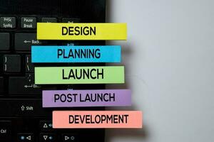 Design, Planning, Launch, Post Launch, Development write on sticky notes with keyboard laptop isolated on white board background photo