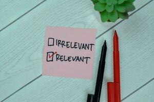 Irrelevant Versus Concept of Relevant write on sticky notes isolated on Wooden Table. photo