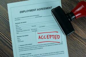 Concept of Approved stamp title on employment agreement isolated on Wooden Table. photo