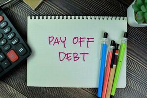 Concept of Pay Off Debt write on a book isolated on Wooden Table. photo