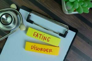 Eating Disorder write on sticky notes isolated on Wooden Table. photo