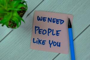 Concept of We Need People Like You write on sticky notes isolated on Wooden Table. photo