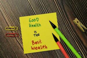 Good Health is the Best Wealth write on sticky note isolated on Wooden Table. Motivation or Financial Concept photo