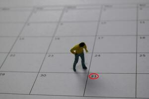 Miniature people thingking salary and looking at down 31 date end of a month. photo