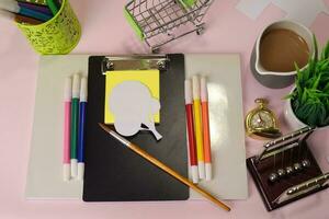 Top view of the cutting paper illustration a trees on a pink table, preparing to do homework in a clipboard. Drawing Working Desk Concept photo