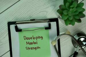 Developing Mental Strength write on sticky notes isolated on Wooden Table. photo