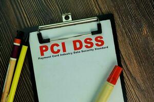 PCI DSS - Payment Card Industry Data Security Standard write on a paperwork isolated on Wooden Table. photo