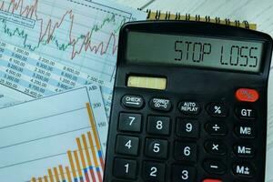 Concept of Stop Loss write on calculator isolated on Wooden Table. photo