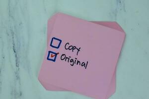 Concpet of Copy or Original write on sticky notes isolated on Wooden Table. photo