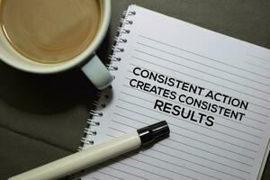 Consisten Action Creates Consistent Results text on the Book isolated on office desk background photo
