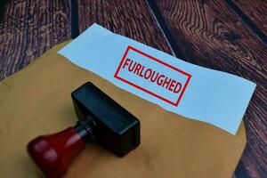 Red Handle Rubber Stamper and Furloughed text Isolated on wooden table background photo