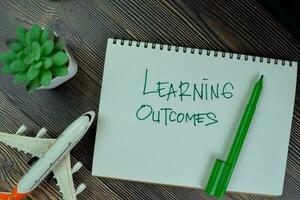 Learning Outcomes write on a book isolated on Wooden Table. photo