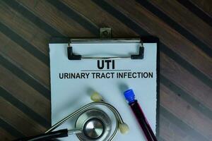 UTI - Urinary Tract Infection write on a paperwork isolated on Wooden Table. photo