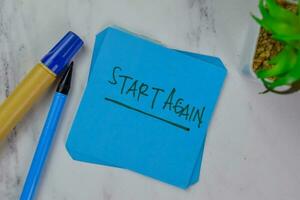 Start Again write on sticky notes isolated on Wooden Table. photo