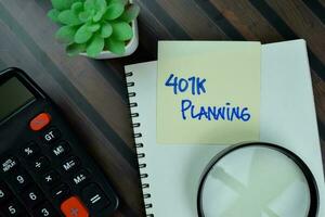 401K Planning write on sticky notes isolated on Wooden Table. photo