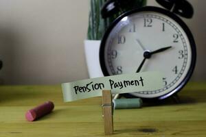 Pension Payment. Handwriting on sticky notes in clothes pegs on wooden office desk photo