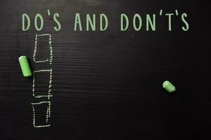 Do's and Don't's written with color chalk. Supported by an additional services. Blackboard concept photo