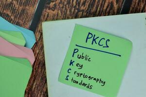 PKCS - Public Key Cryptography Standards write on sticky notes isolated on Wooden Table. photo