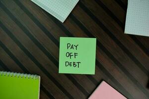 Pay Off Debt write on sticky notes isolated on Wooden Table. photo