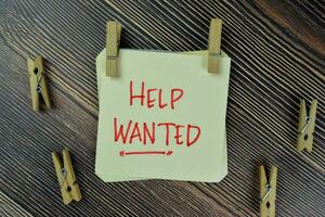 Help Wanted write on sticky notes isolated on Wooden Table. photo