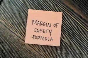 Concept of Margin of Safety Formula write on sticky notes isolated on Wooden Table. photo