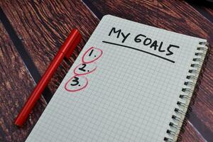 My Goals write on a book and number check Isolated on wooden table background photo