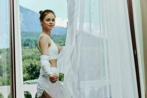 slender woman in a white shirt admires the green nature on the balcony Summer day photo